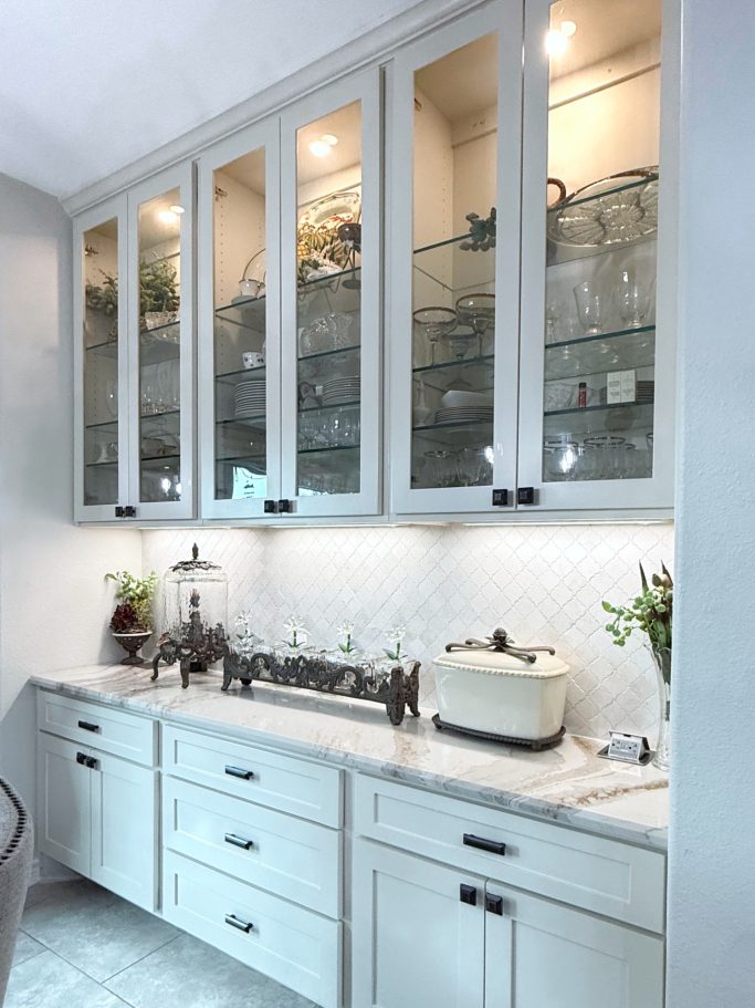 Kitchen wall with glass front upper cabinets and built-in display shelving