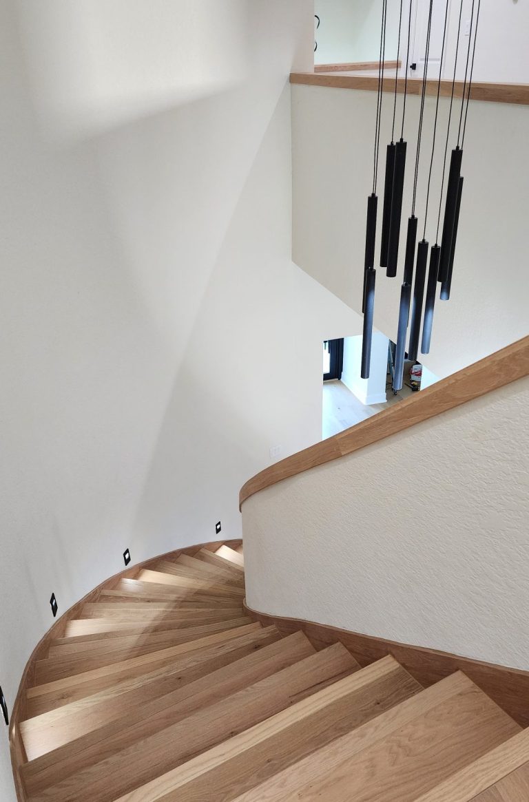 Interior staircase with curved wooden treads following a rounded wall.