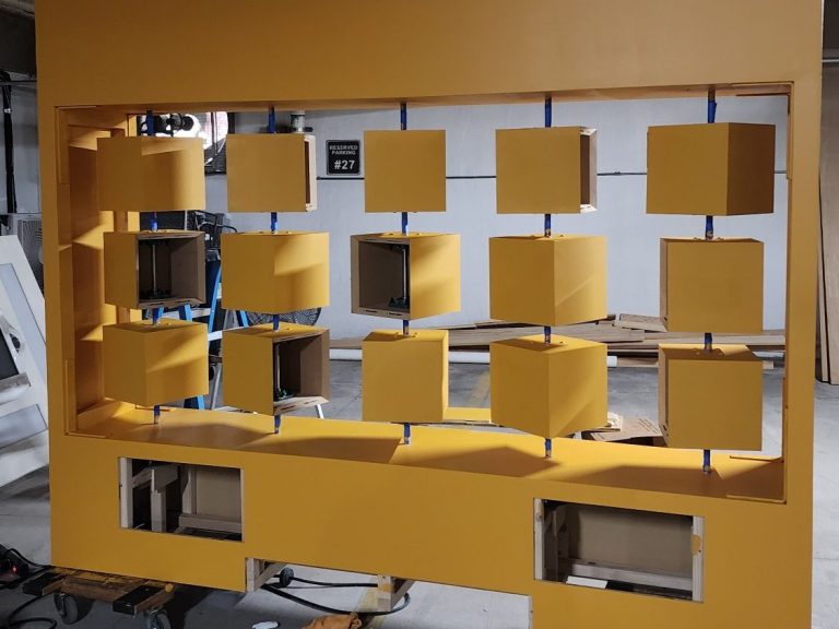 Flip Panel Assembly Yellow flip panel frame with a grid of square openings during assembly.