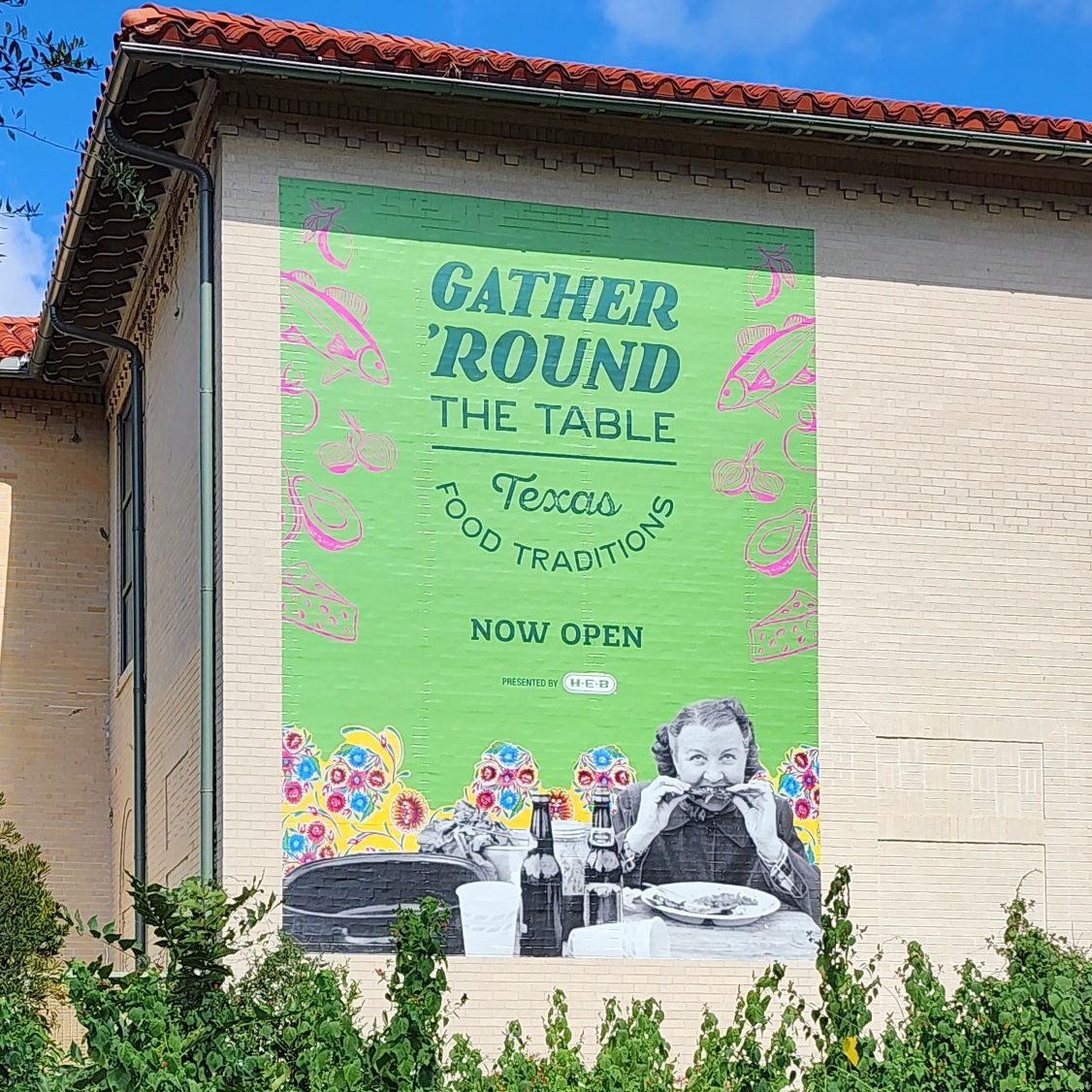 Green exterior mural advertising the Gather 'Round the Table: Texas Food Traditions exhibit.