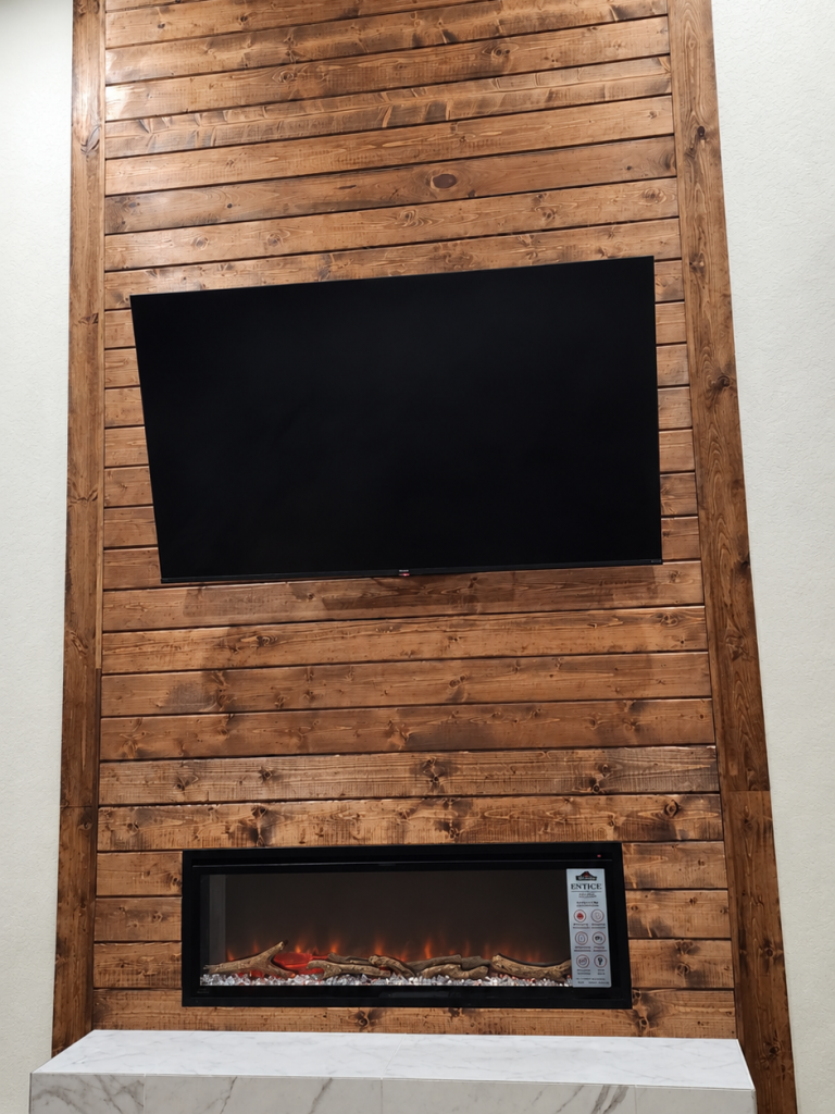 Wood-slat interior feature wall with a television recess and a fireplace below.